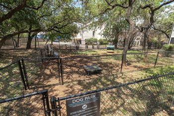 A dog park sign is displayed on a fence.